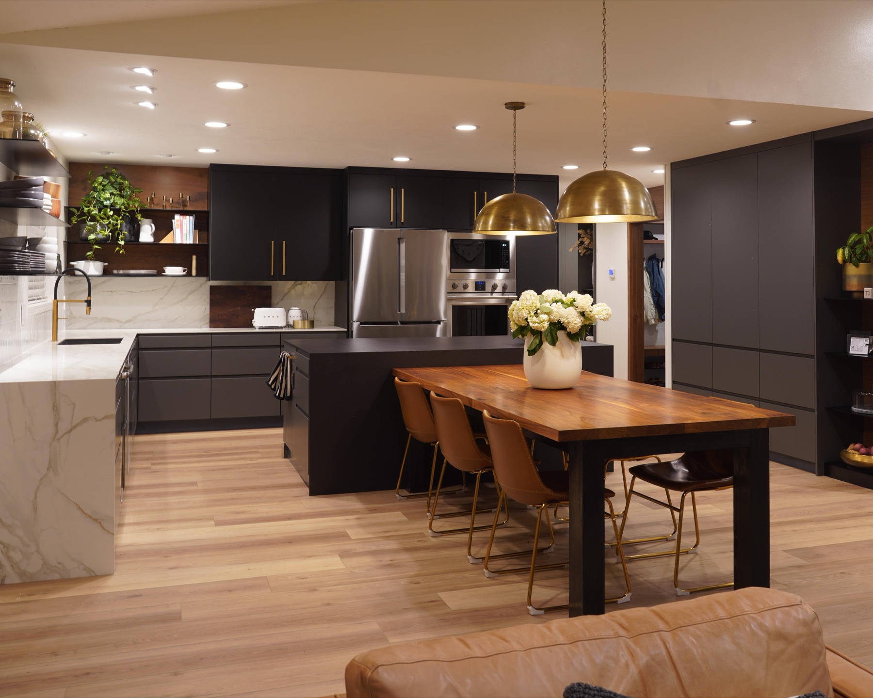Renovated kitchen with black cabinets and brass pendants